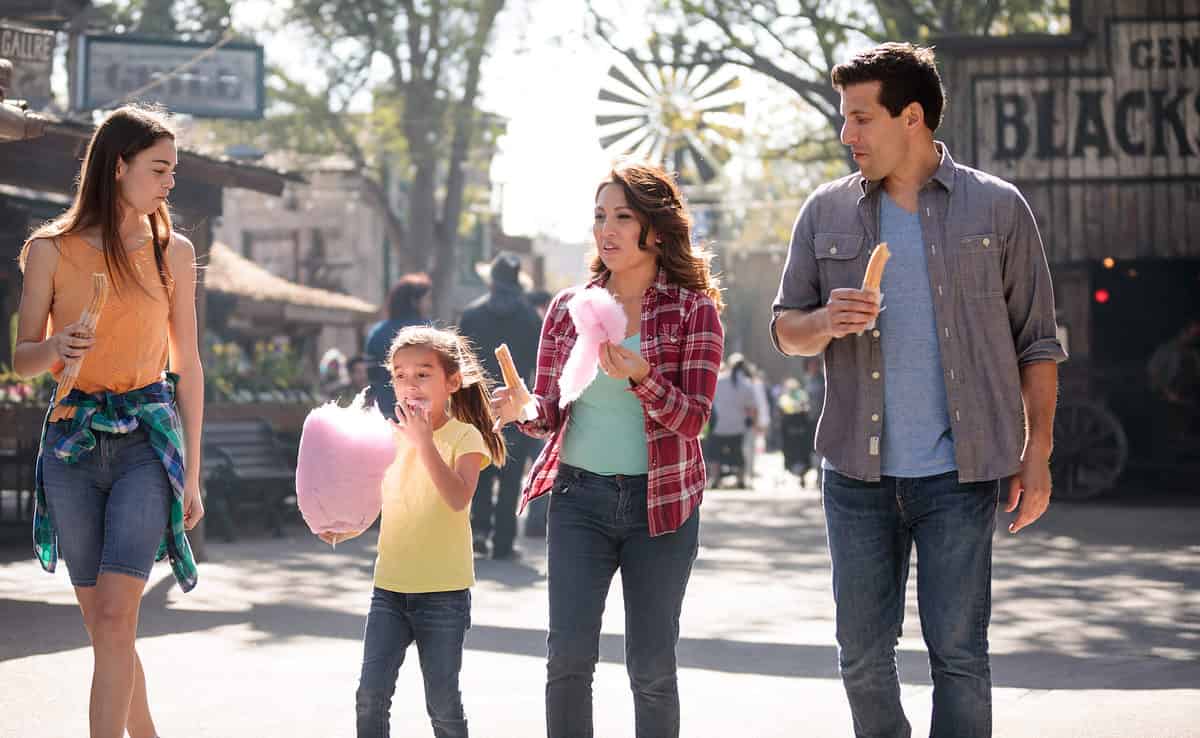 Family eating cotton candy at a park.