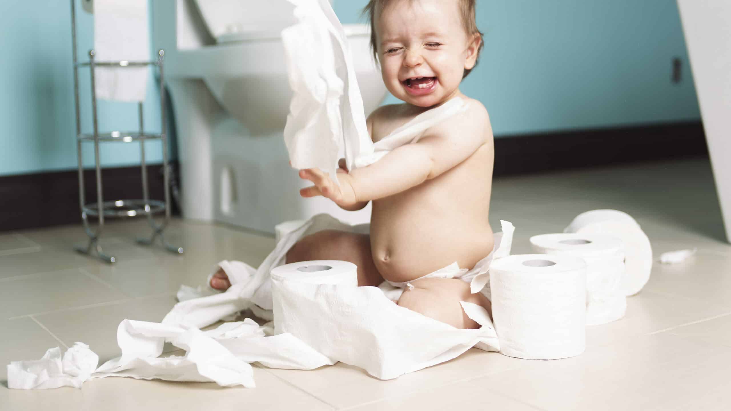 A Toddler ripping up with toilet paper in bathroom