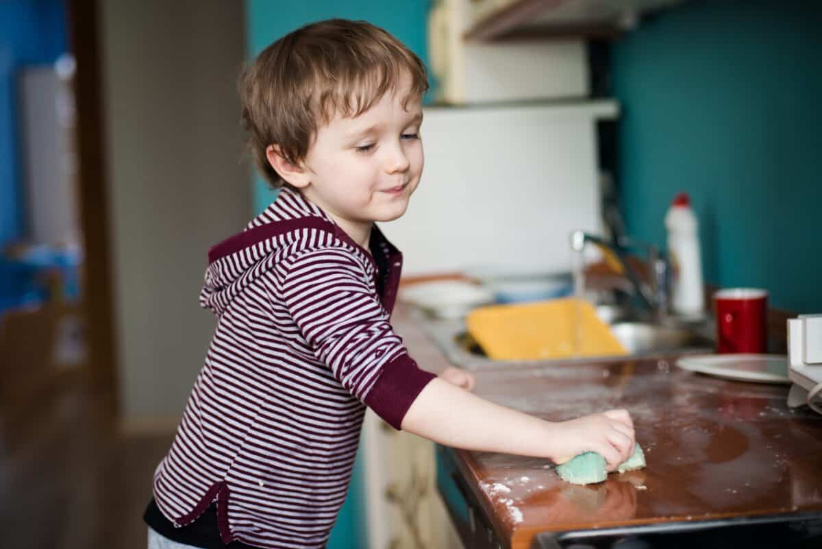 Boy cleaning the kitchen after making dinner