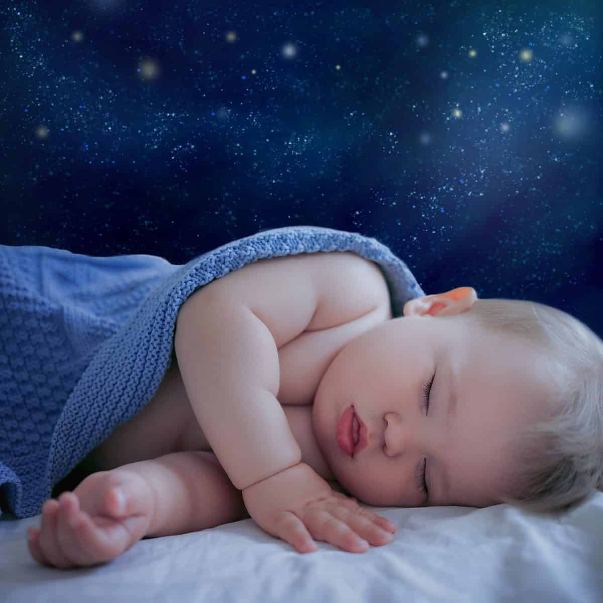 cute baby 1 year old sleeping on the background of the starry sky or space, good night and magical dreams concept