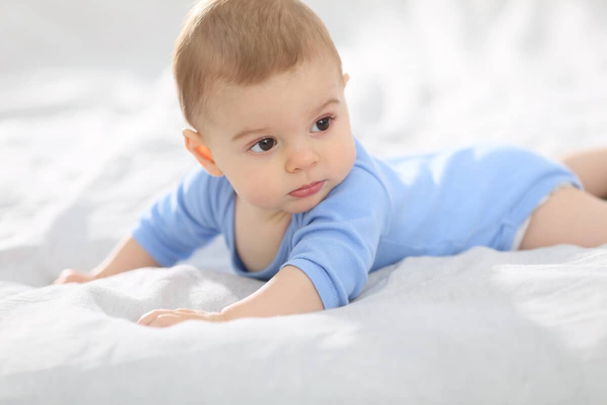 8-month-old baby boy laying on bed