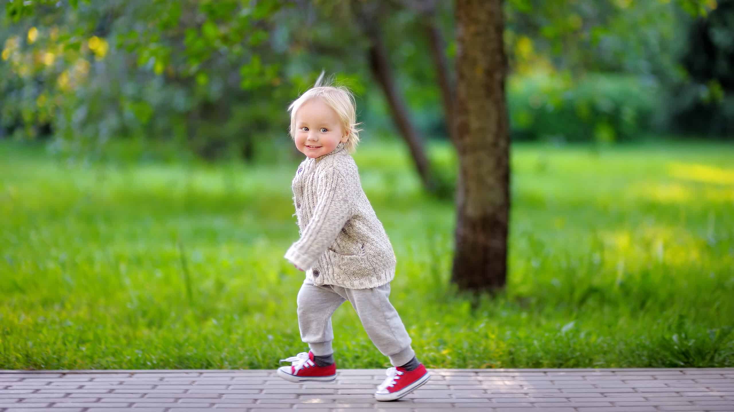 Toddler boy running in the park at the spring or summer day