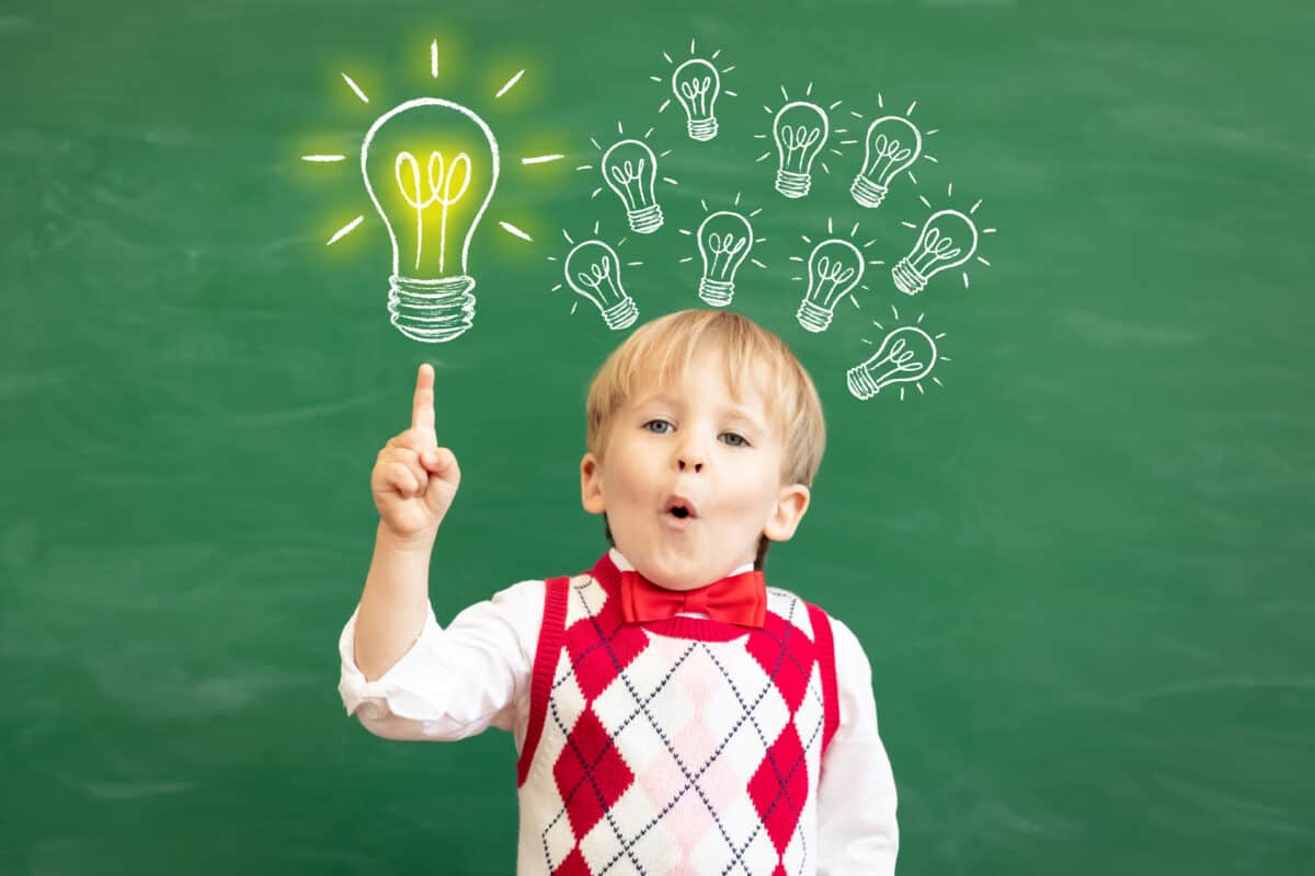 Bright idea! Surprised child student pointing finger up! Happy kid against green chalkboard. Online education and e-learning concept. Back to school