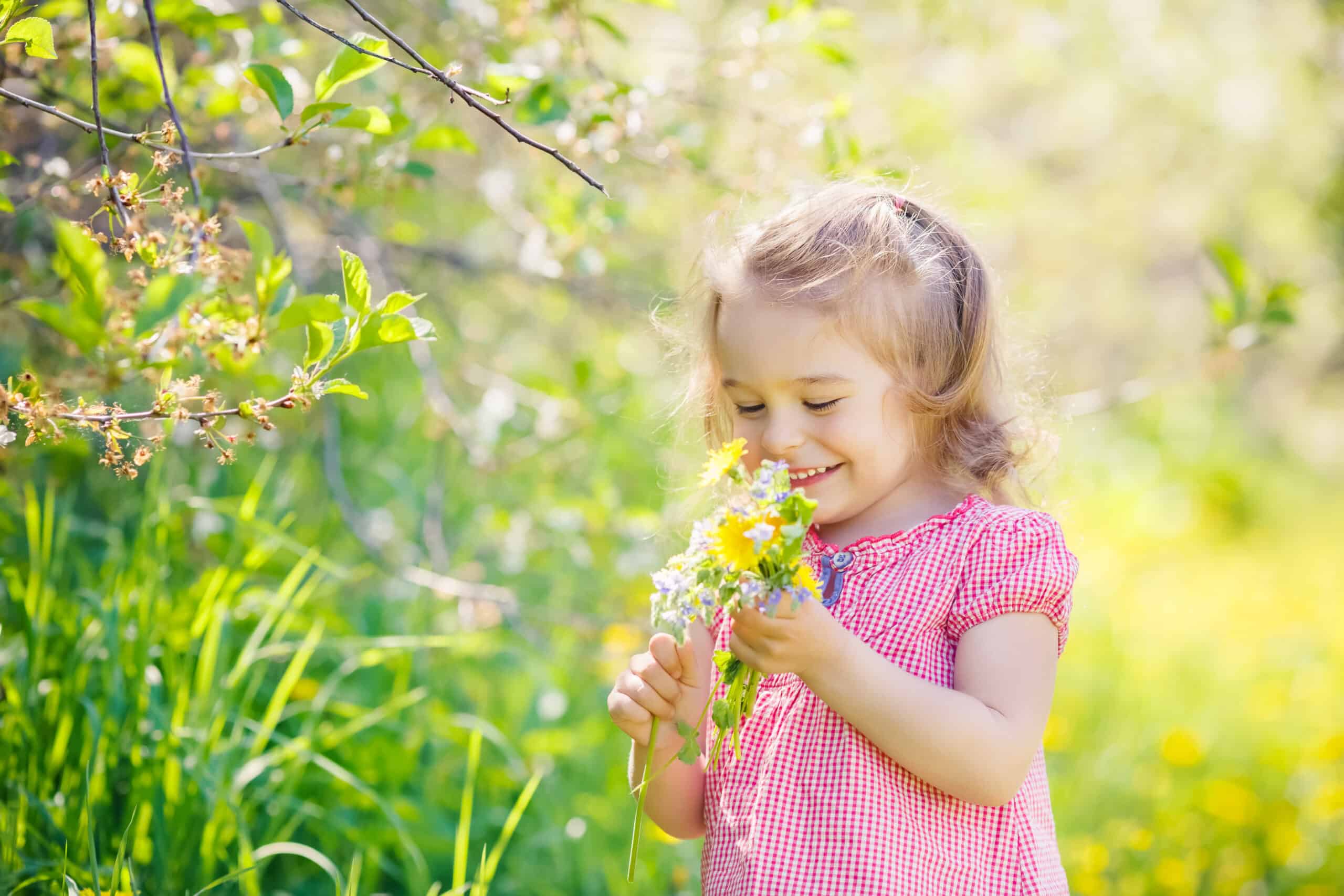 Happy little girl playing with bouquet in sunny park