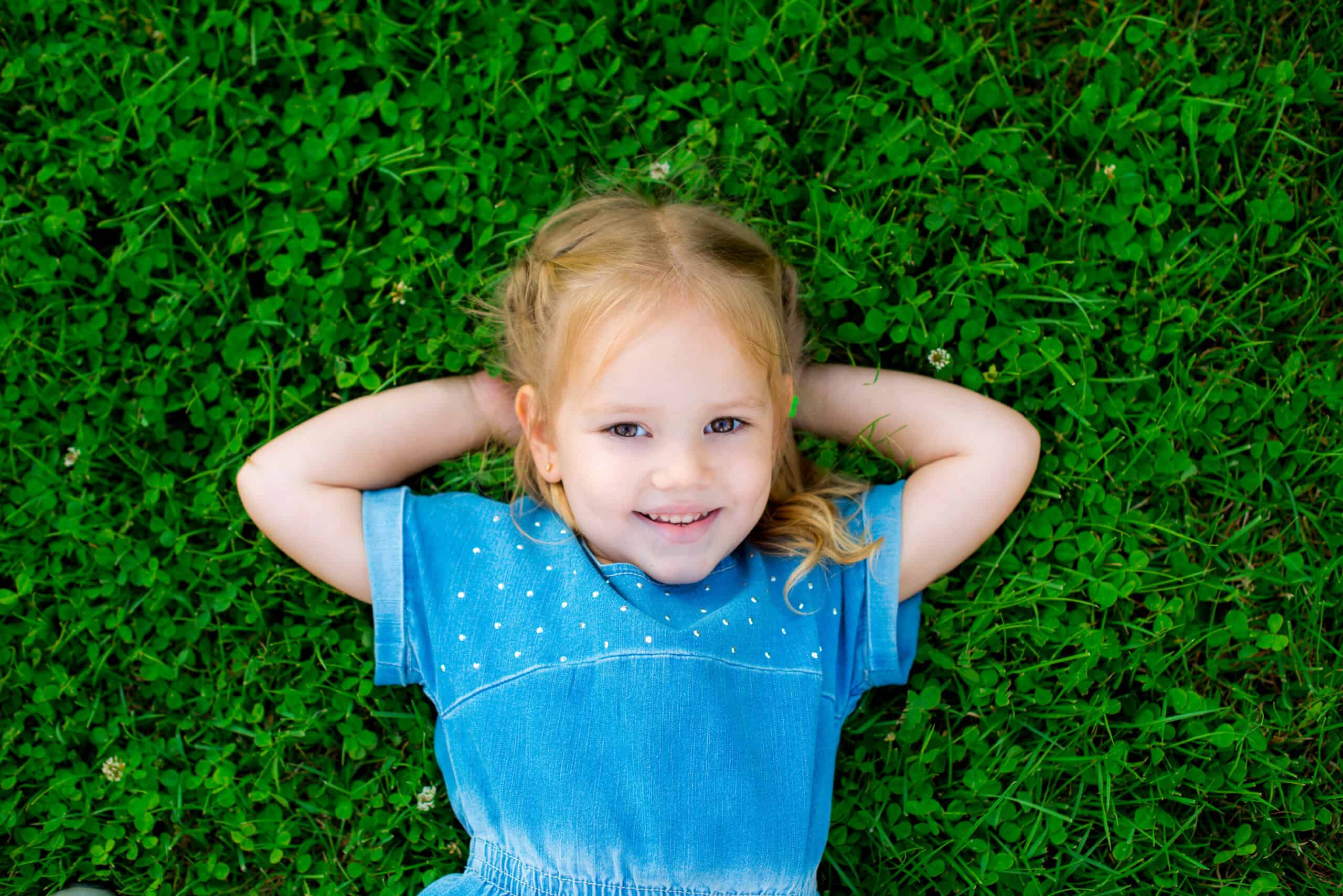 Happy cute girl on green grass in spring park. Healthy lifestyles concept.