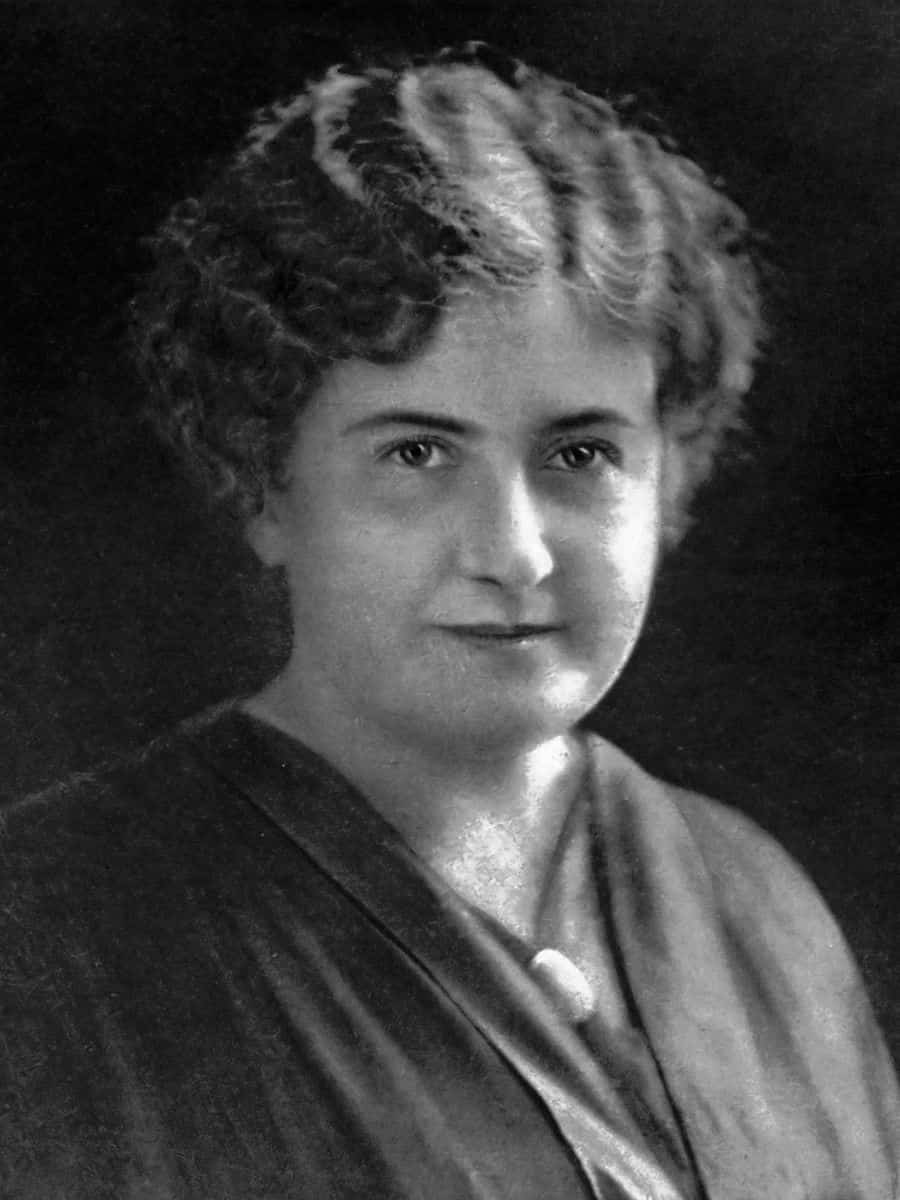black and white portrait of Maria Montessori. She is facing the camera, and appears to be serene. Sh is light-skinned and has wavy dark ear-length hair that she parts in the left. She is dressed in black. hair