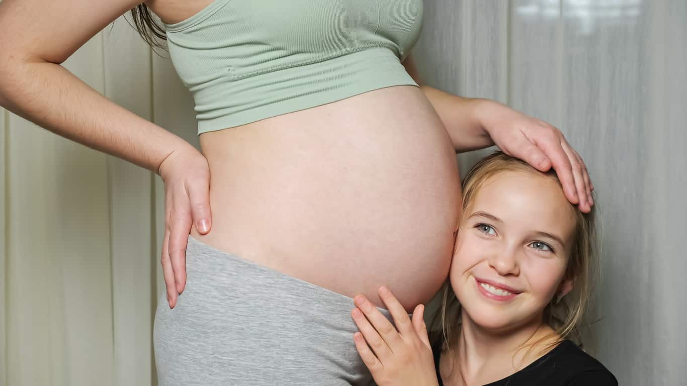 Smiling pregnant woman in headphones touching her belly. Pregnancy,  maternity, preparation and expectation concept Stock Photo