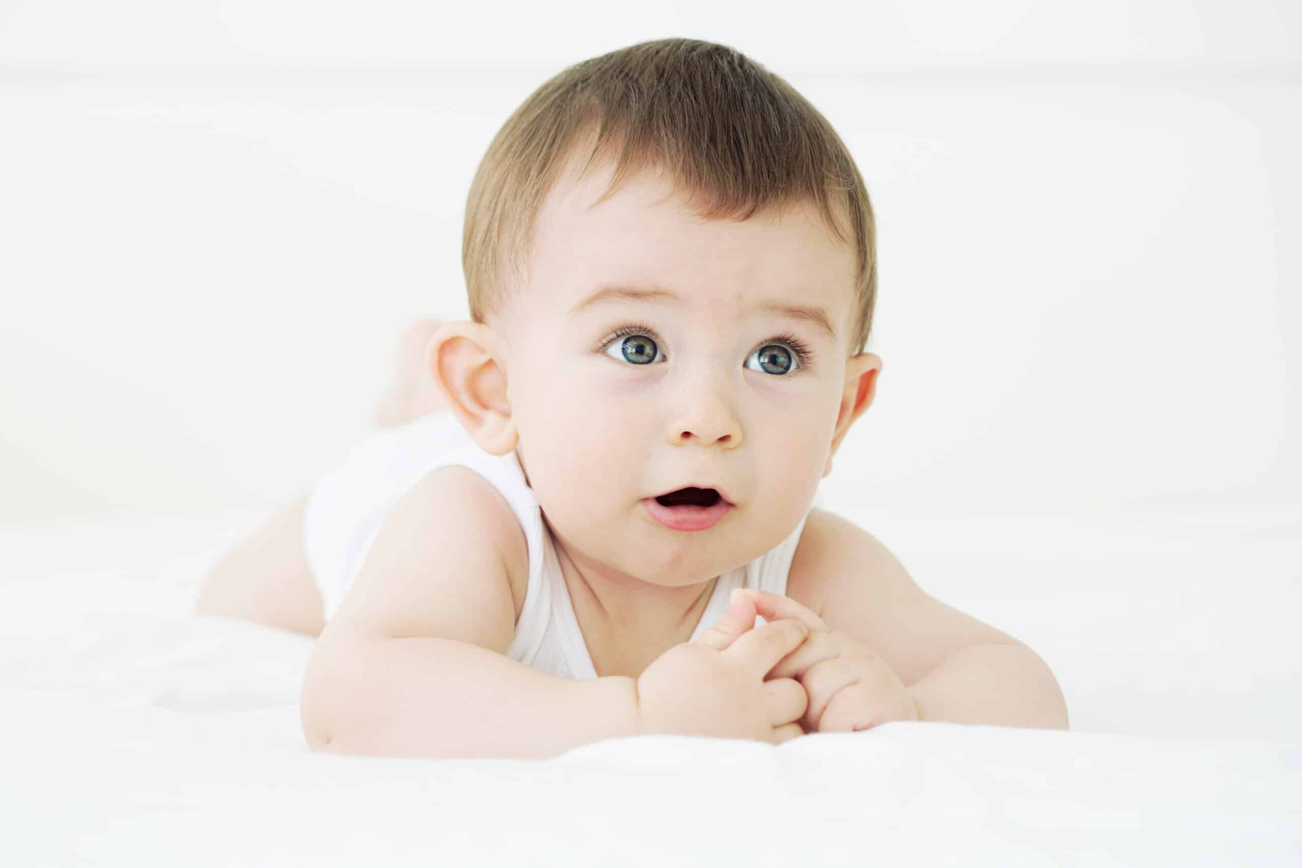 Adorable baby boy lying on the bed and trying to talk