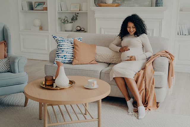 Pregnant woman smiling and connecting with baby.