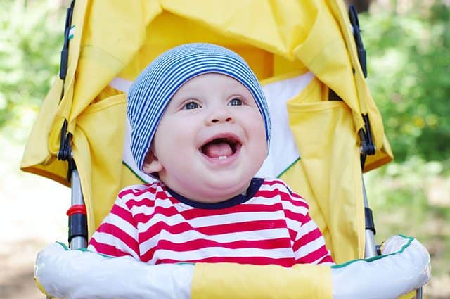 Happy baby on the yellow baby buggy