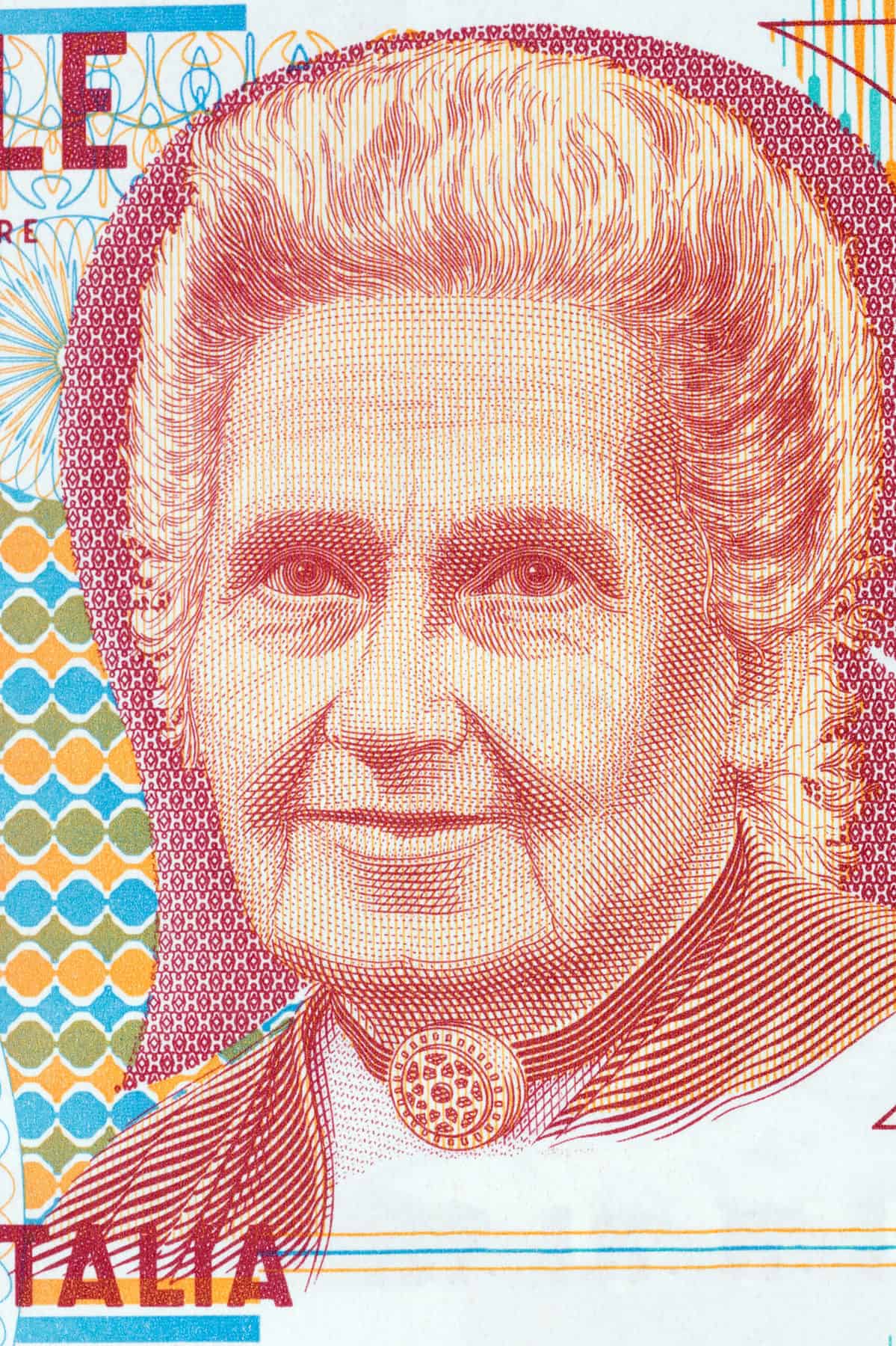 An engraving /etcing of Maris Montessori on an Italian bank note. She is etched in deep red and ecru. Yellow, olive and light blue dots and diamonds are visible to her left. The word TALIA is visible in the lower left frame. The I was apparently cropped out of the photo. oops.