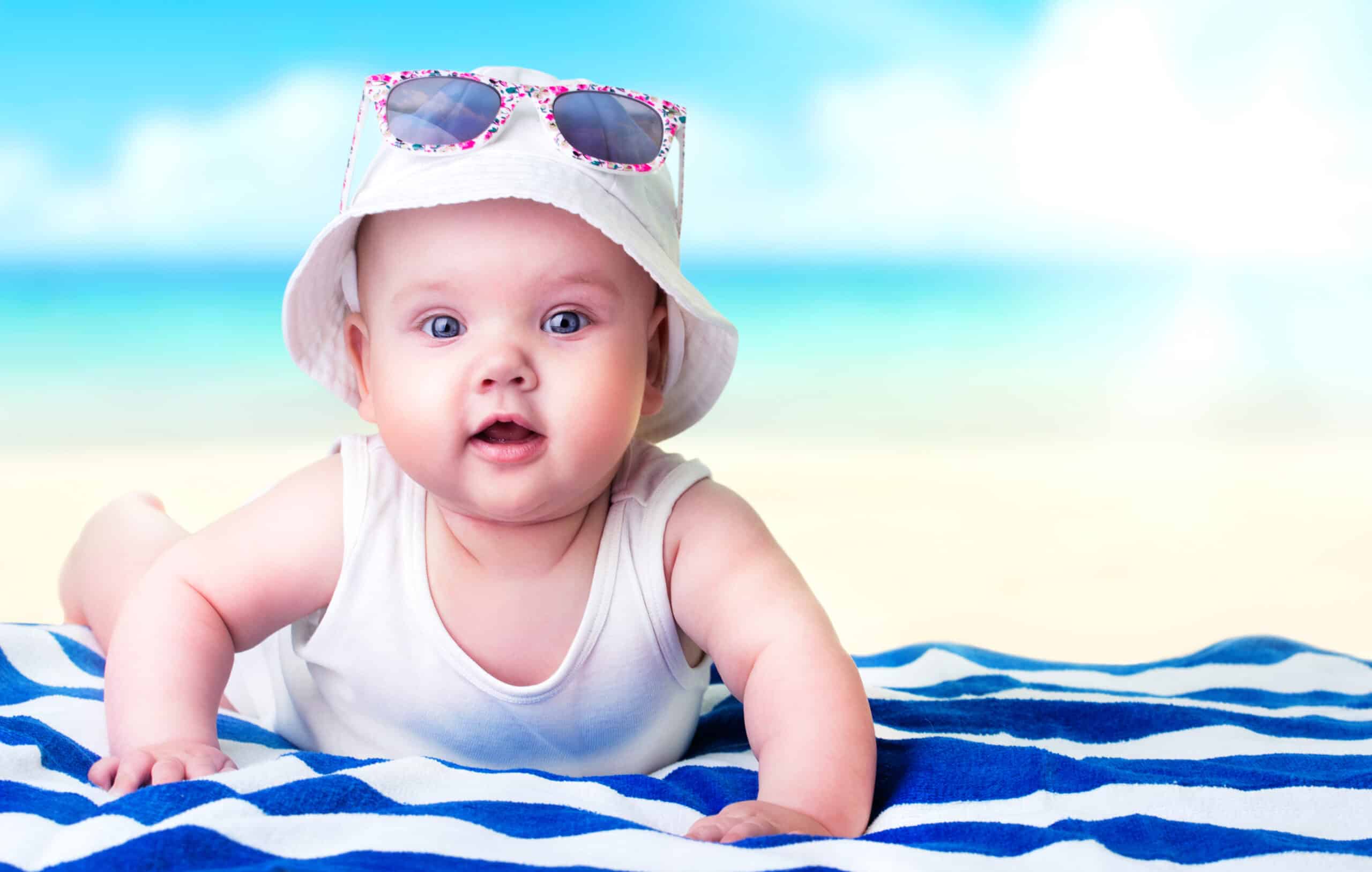 Baby girl's funny face on a beach towel ocean background. Caucasian newborn child summer resort concept.Advertisement travel banner.