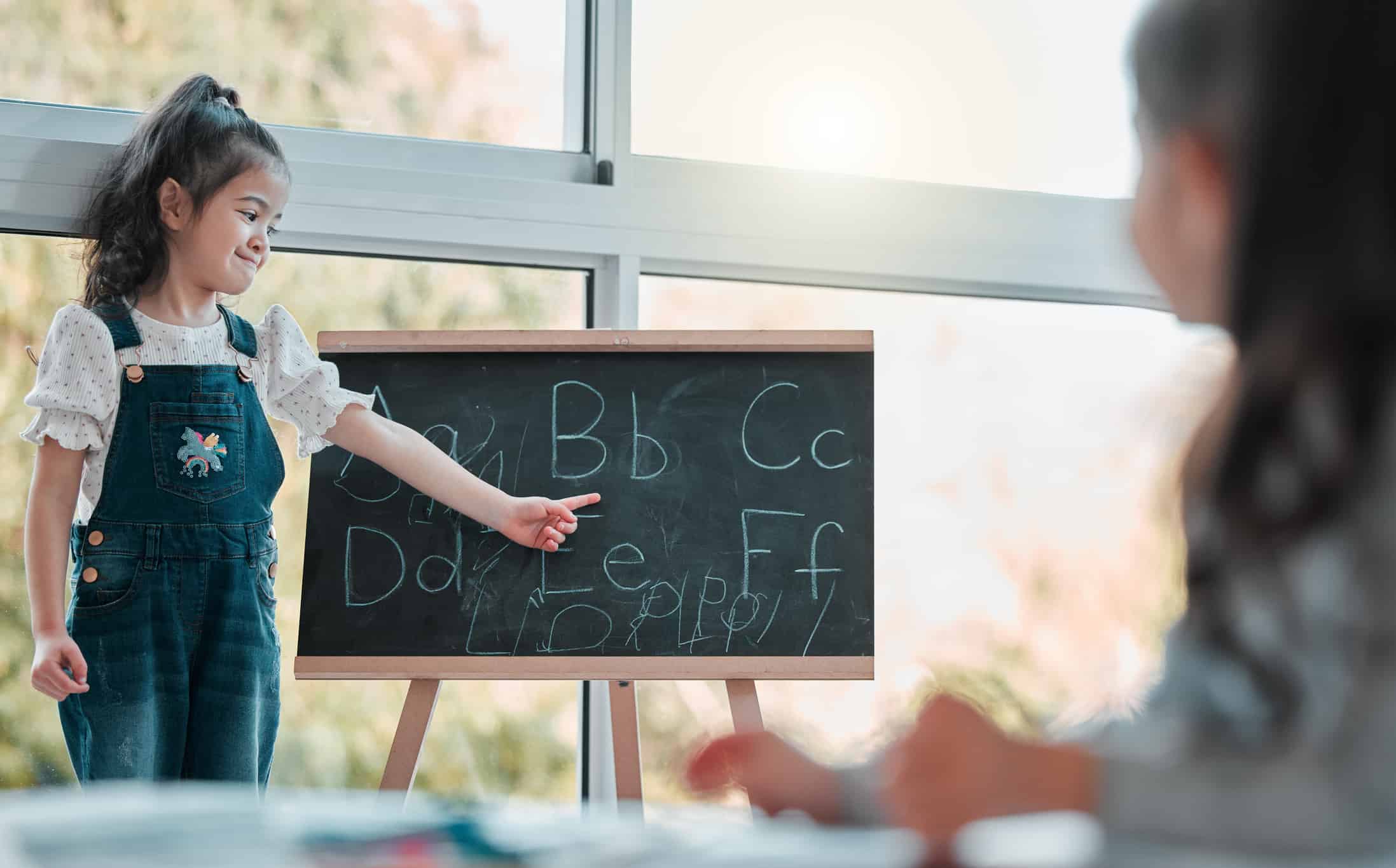 Young girl learning letters on a blackboard