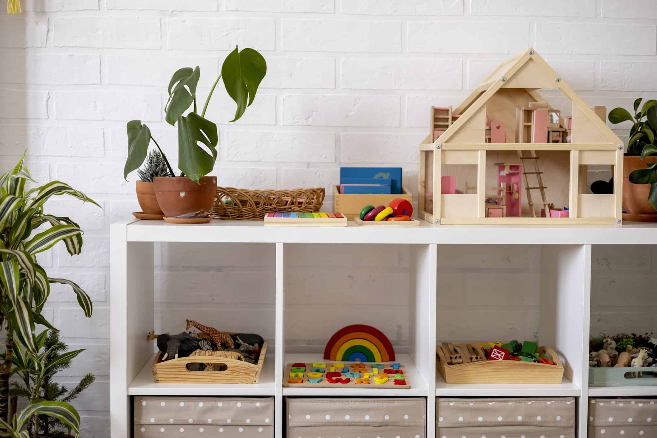 Material for Montessori school. White shelves in a room with neatly arranged toys.