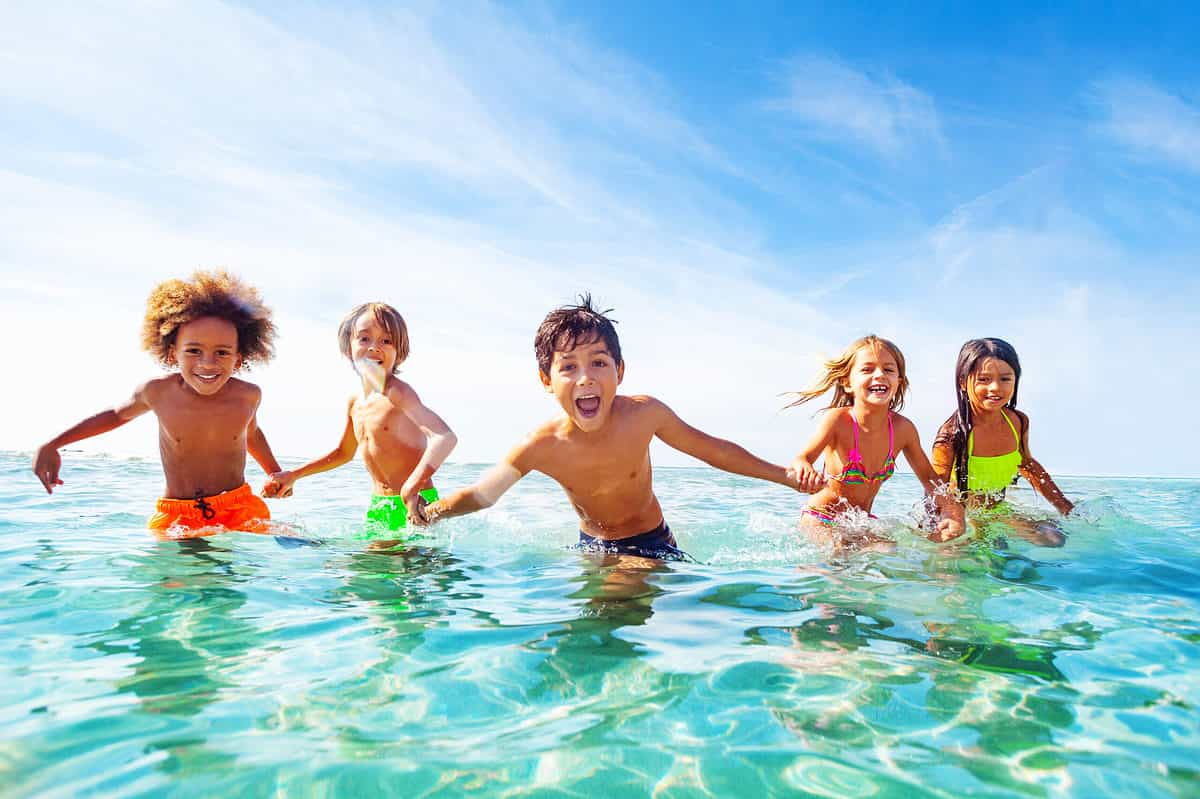 Children holding hands in water.