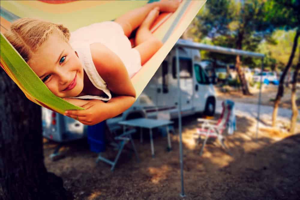 Camping RV travel with camper, summer beach. Happy smiling beauty girl on motorhome vacation.