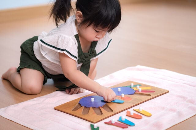 Preschool girl plays with wooden Montessori activity