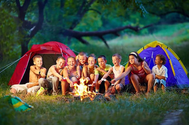 Kids around a campfire with tents