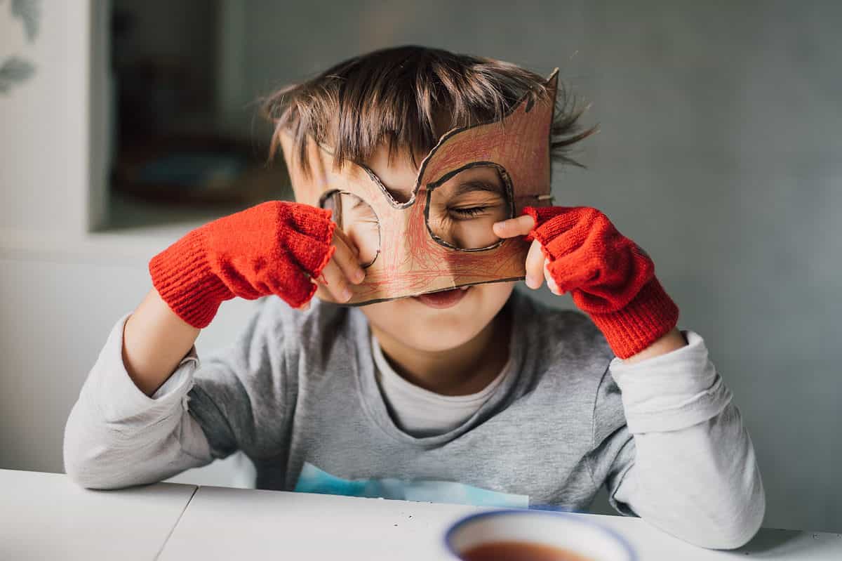 Child with a homemade superhero mask cut out from cardboard.