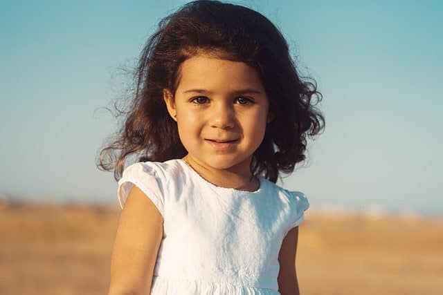 A portrait of a Muslim little girl in the desert. A girl of oriental appearance at sunset. The emotional face of a beautiful Egyptian girl