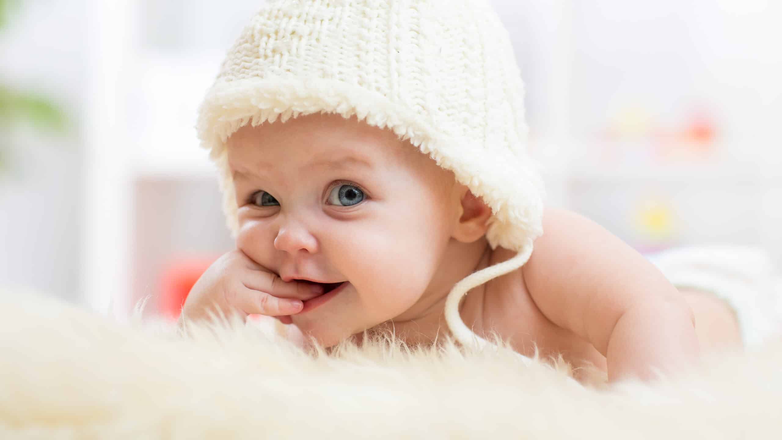 A cute little baby girl looked into the camera and wore a white hat.