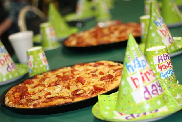 Pizza on table with birthday hats.