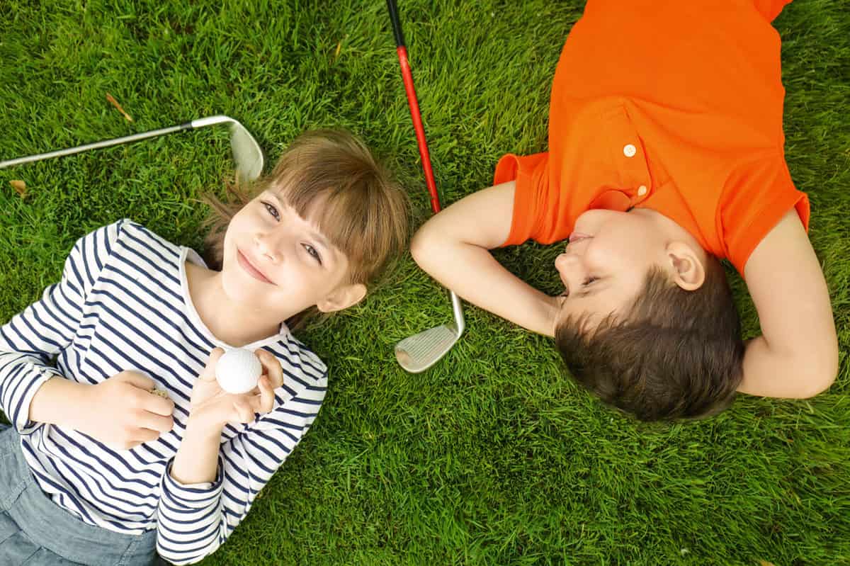 Cute,Children,With,Ball,And,Drivers,Lying,On,Golf,Course