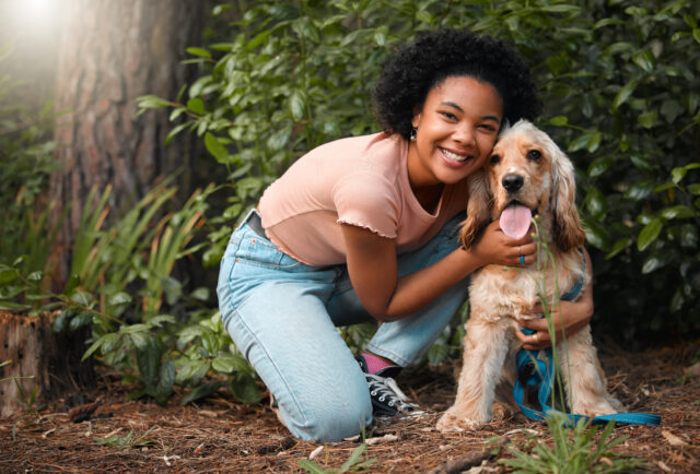 Full length portrait of an attractive young woman and her Cocker Spaniel puppy outside