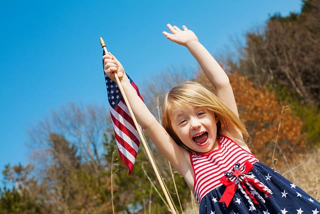 Happy girl with American flag outside
