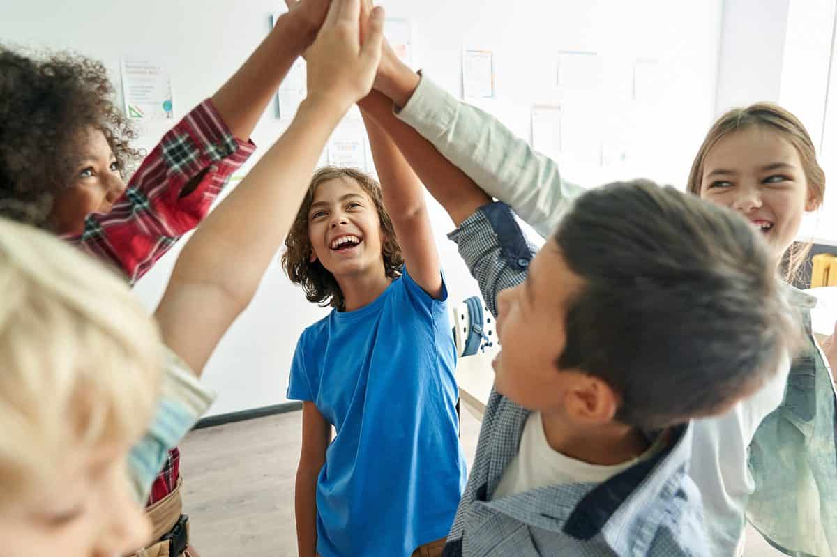 Kids high fiveing in a classroom. 