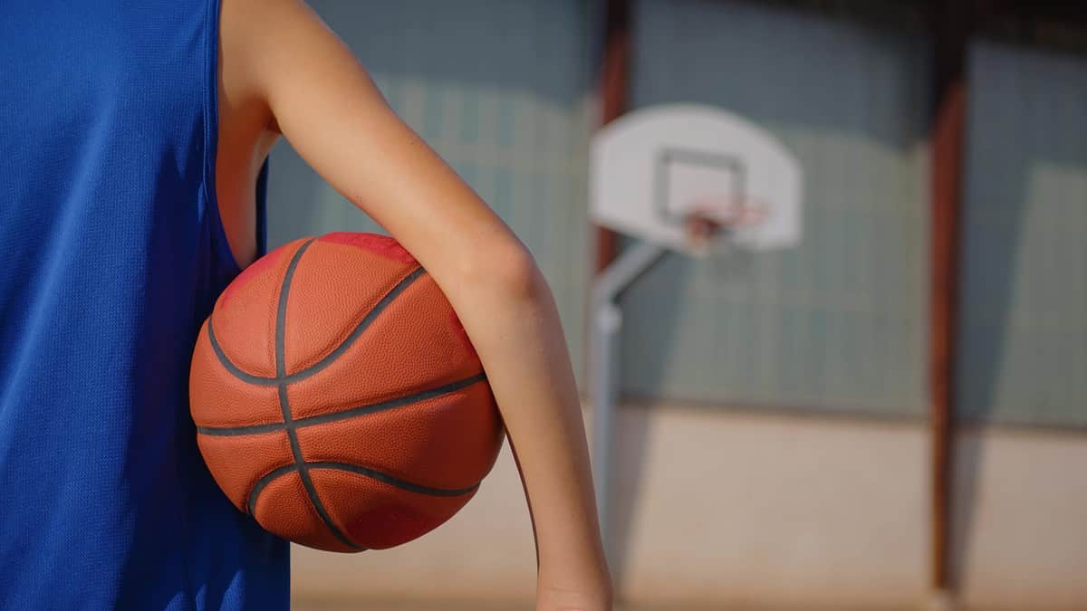 basketball in child's arm, hoop in background