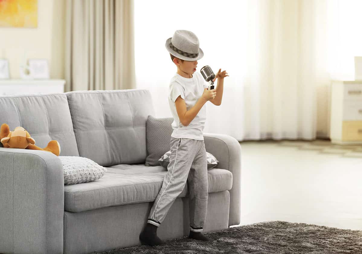 Little boy singing into a microphone in his living room