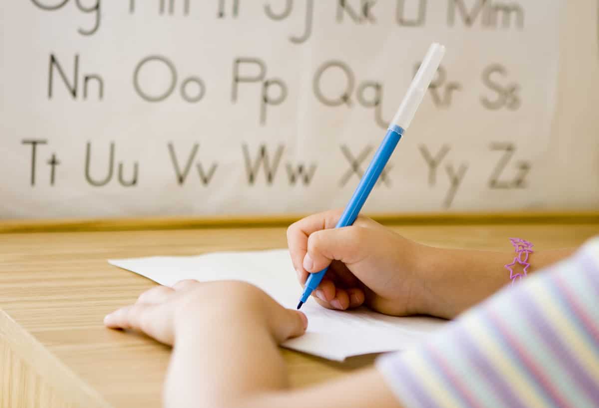 Child writing on white piece of paper
