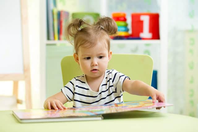 Little toddler girl reading a book