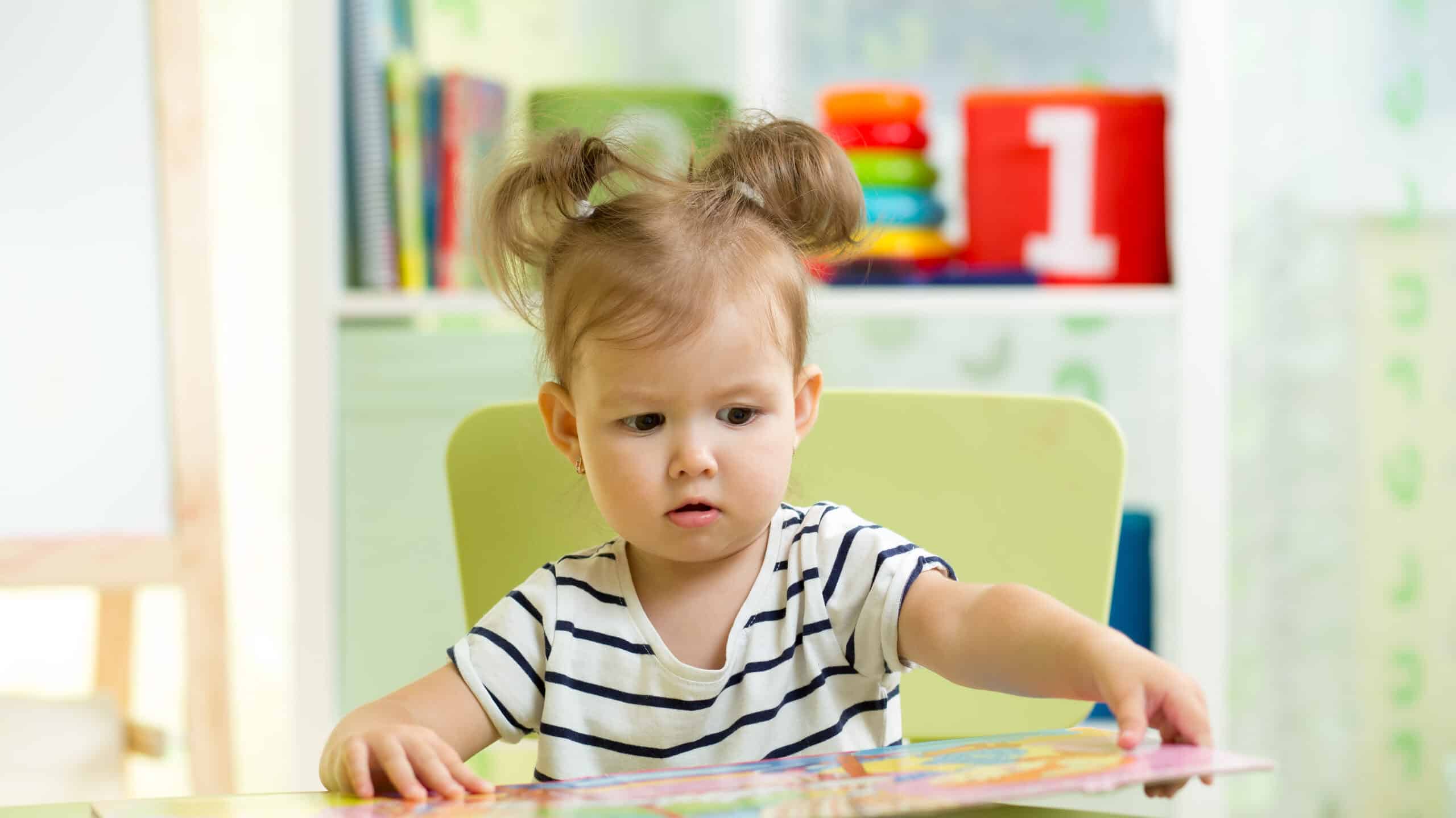 Little toddler girl reading a book