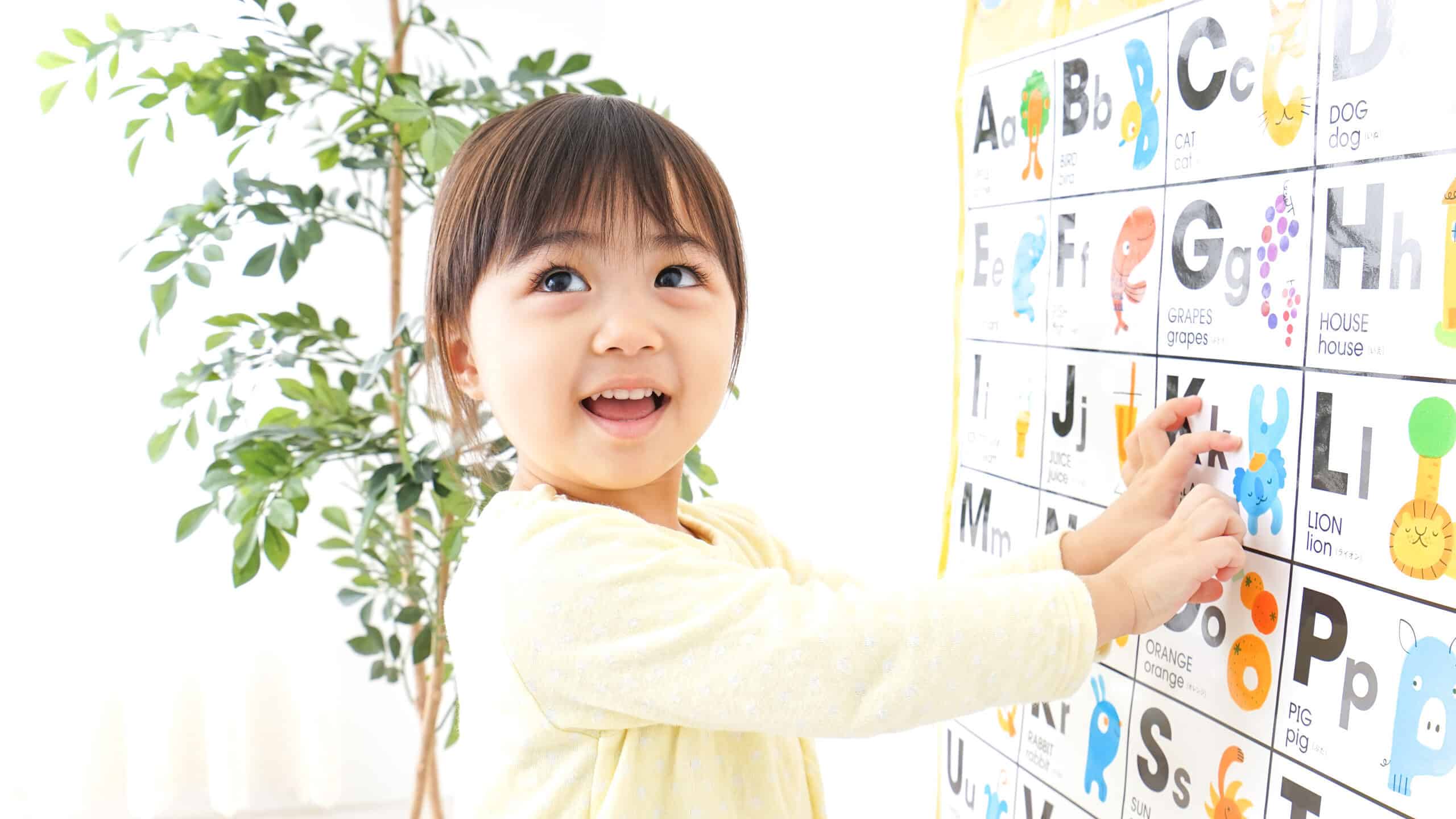 Happy girl pointing at alphabet on chart