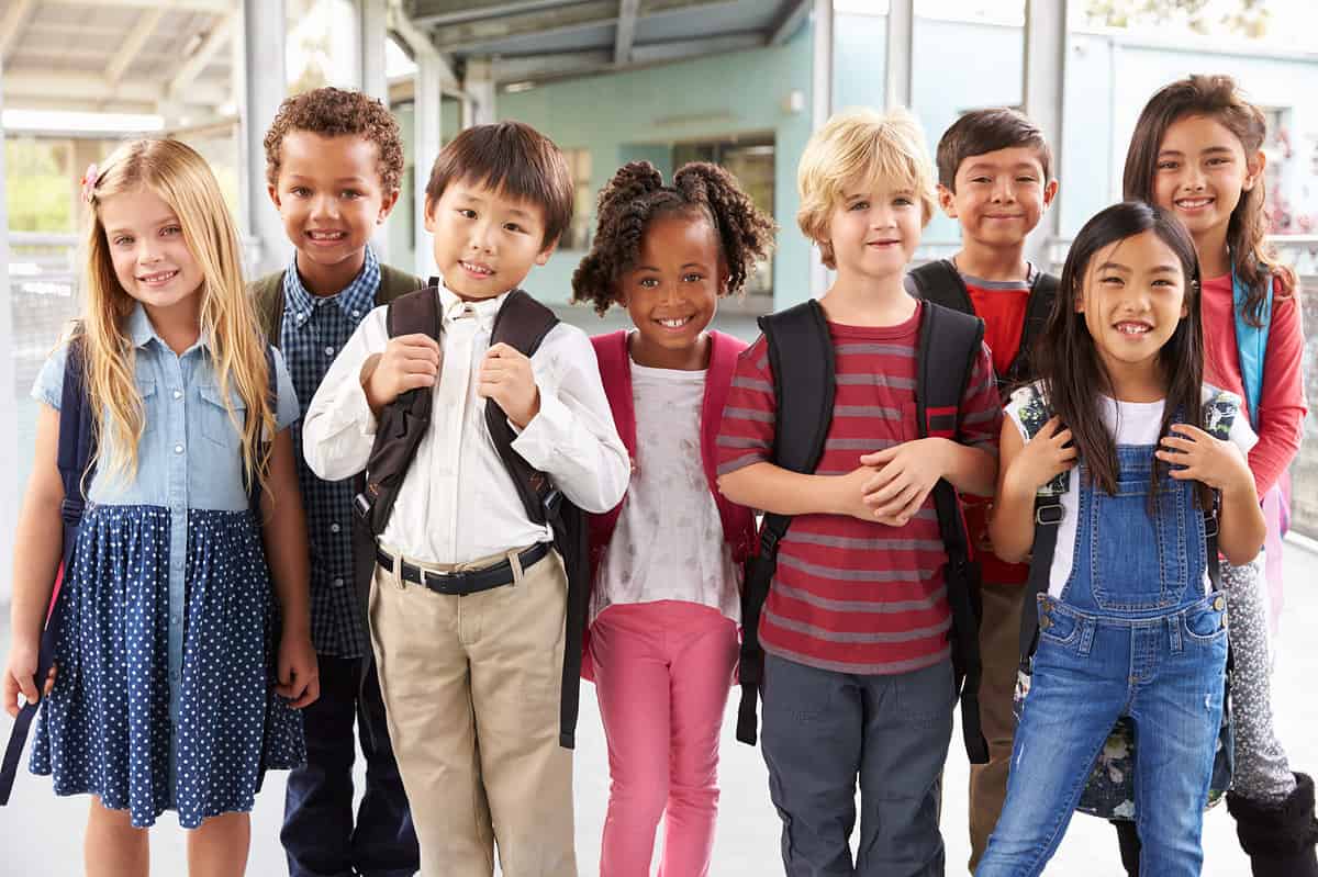 A group of elementary school kids standing in a hallway. 