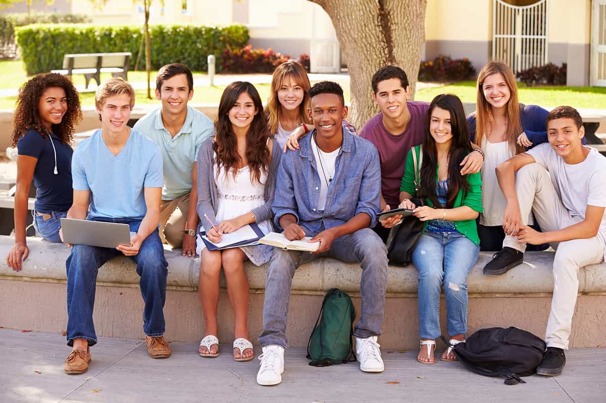 High school students seated outside the class under a tree.