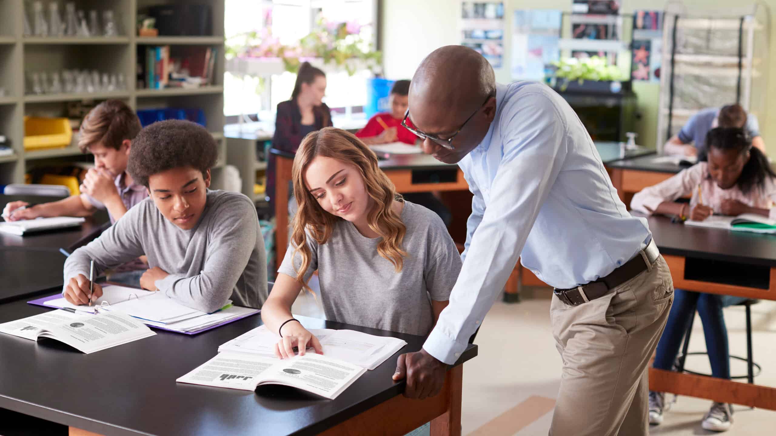 Male High School Tutor Teaching Students In Biology Class