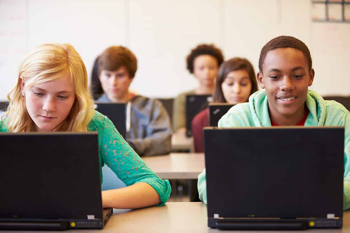 High school students in class with laptops. 