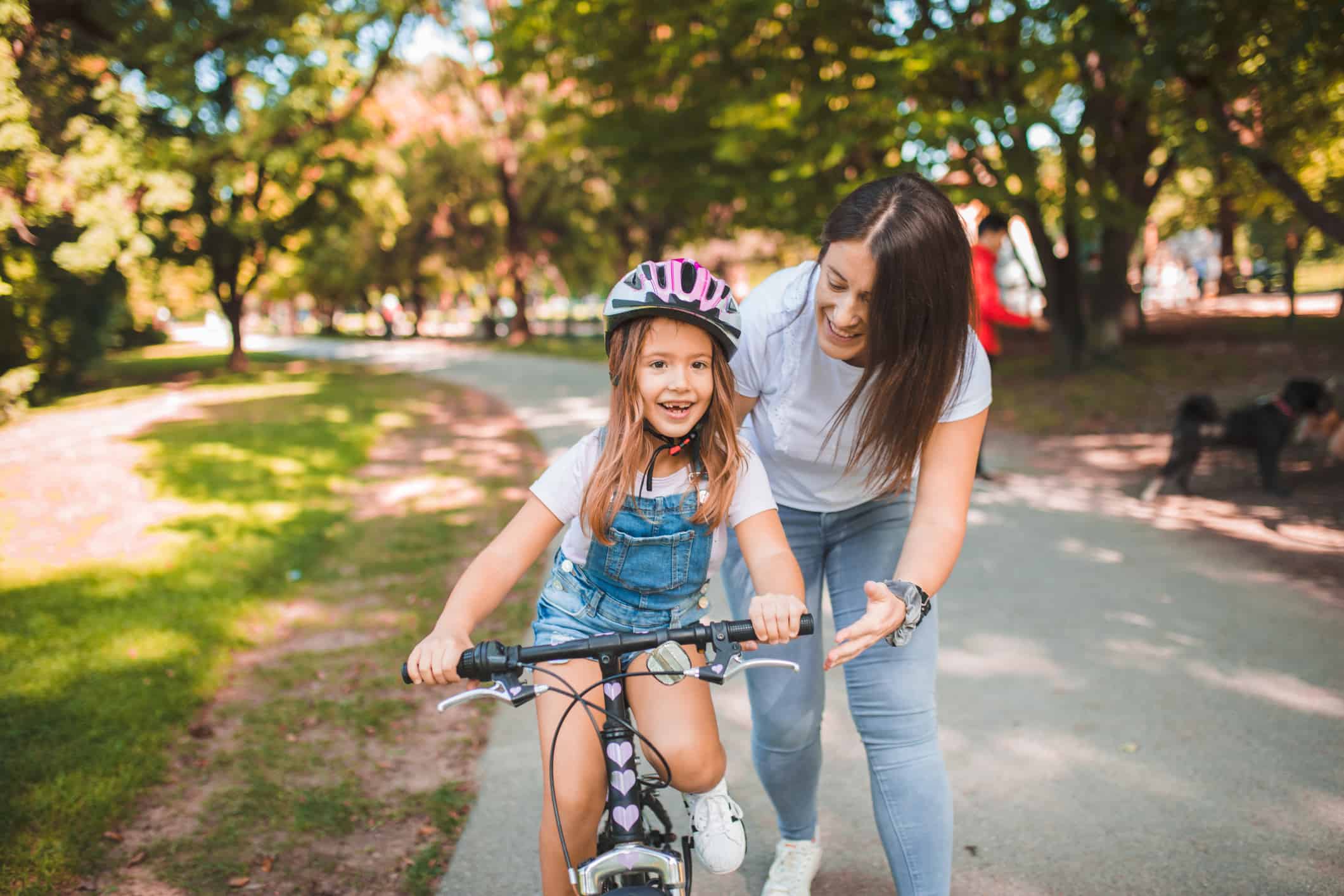 Mother teaches her daughter to ride a bicycle in the park