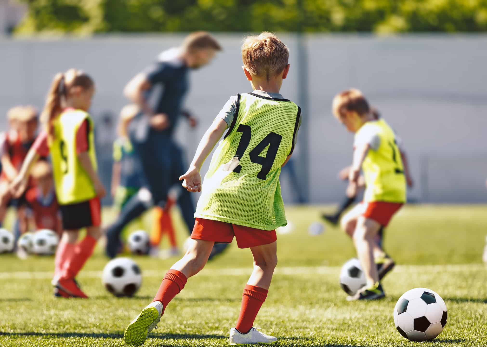 School Children Play Soccer Football Training Game With Coach. Kids Kicking Sports Balls on Grass Field. Football Practice For Youth