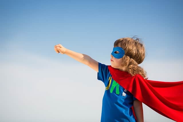 Superhero kid against blue sky background. Girl power concept