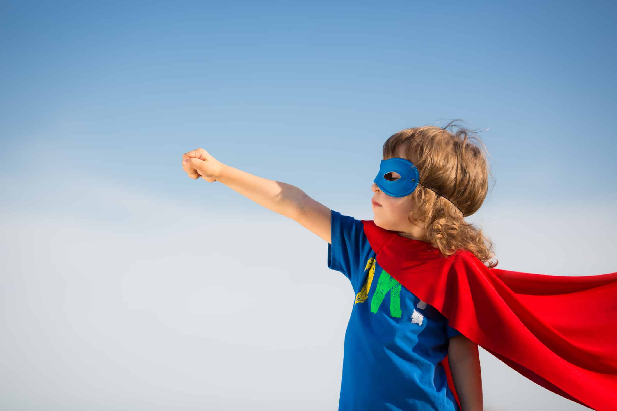 Superhero kid against blue sky background. Girl power concept