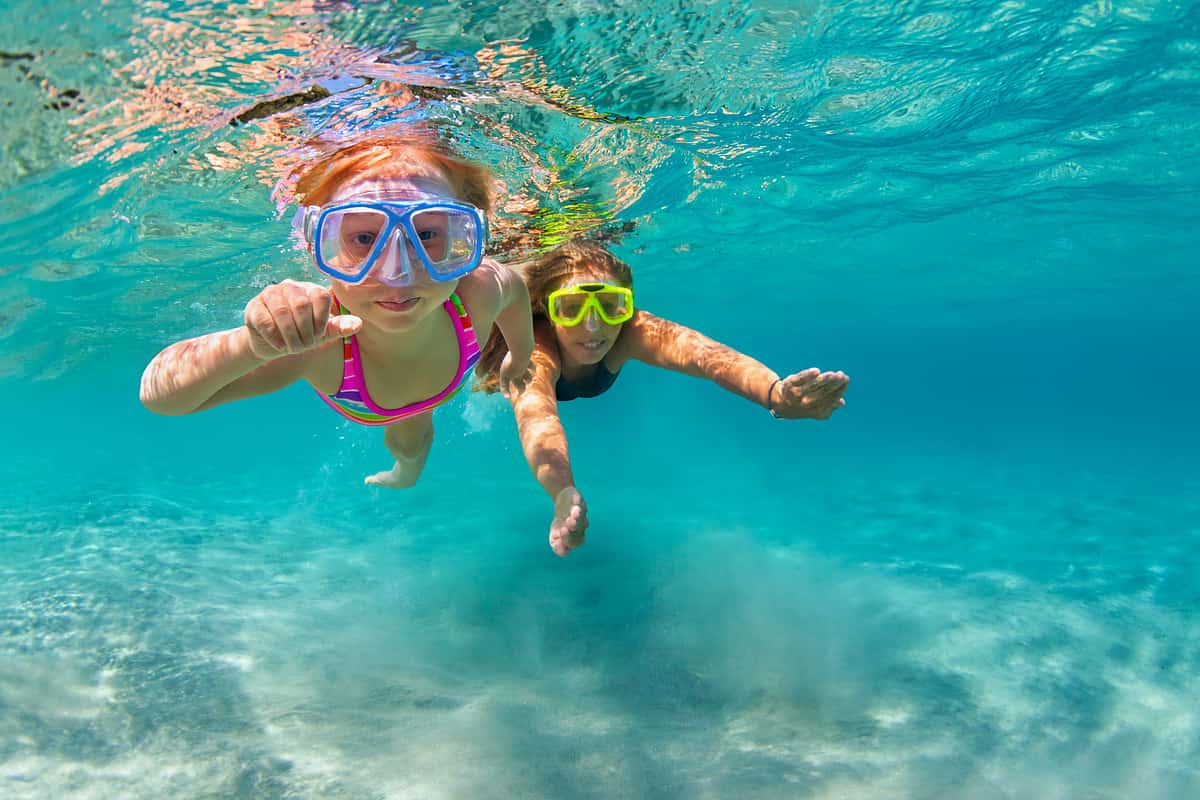 Happy family - mother with baby girl dive underwater with fun in sea pool. Healthy lifestyle, active parent, people water sport outdoor adventure, swimming lessons on beach summer holidays with child