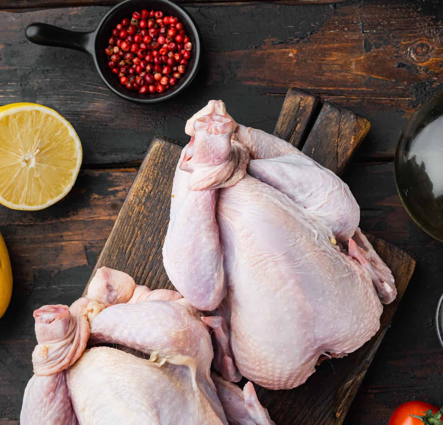 Whole raw free range chicken with ingredients, on old wooden table, top view