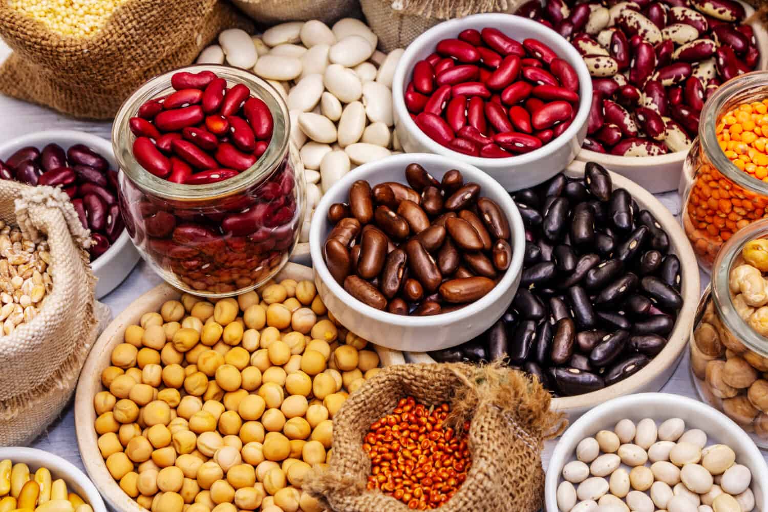 Assorted different types of beans and cereals grains. Set of indispensable sources of protein for a healthy lifestyle. White wooden boards background, close up