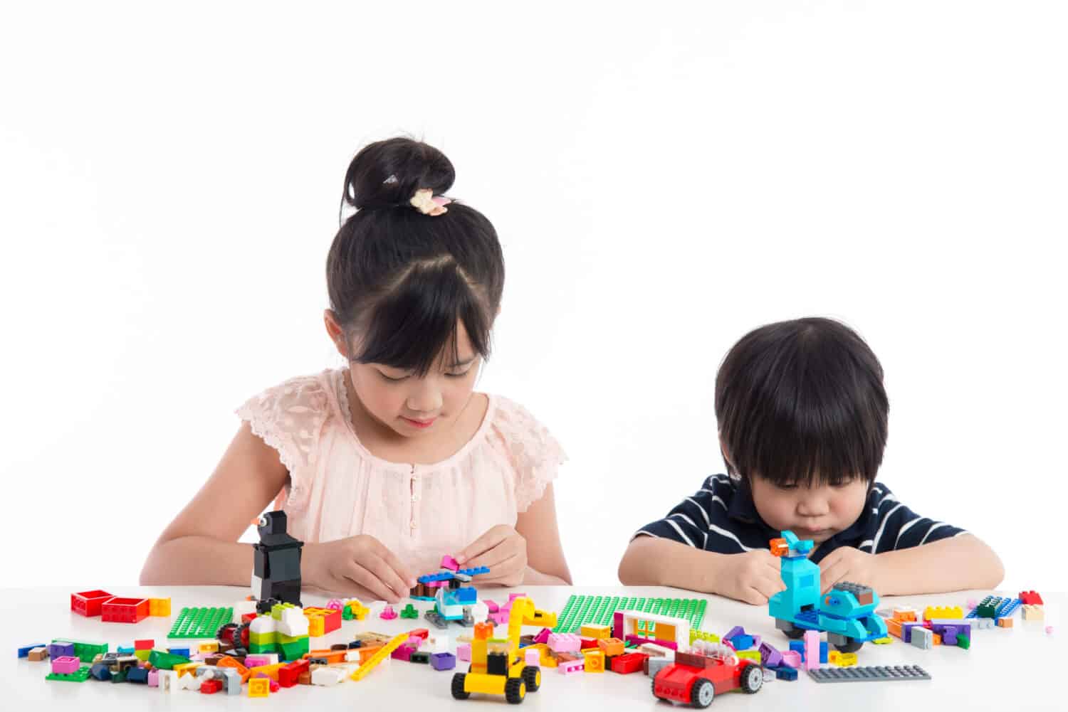 Little asian children playing with colorful construction blocks on white background isolated