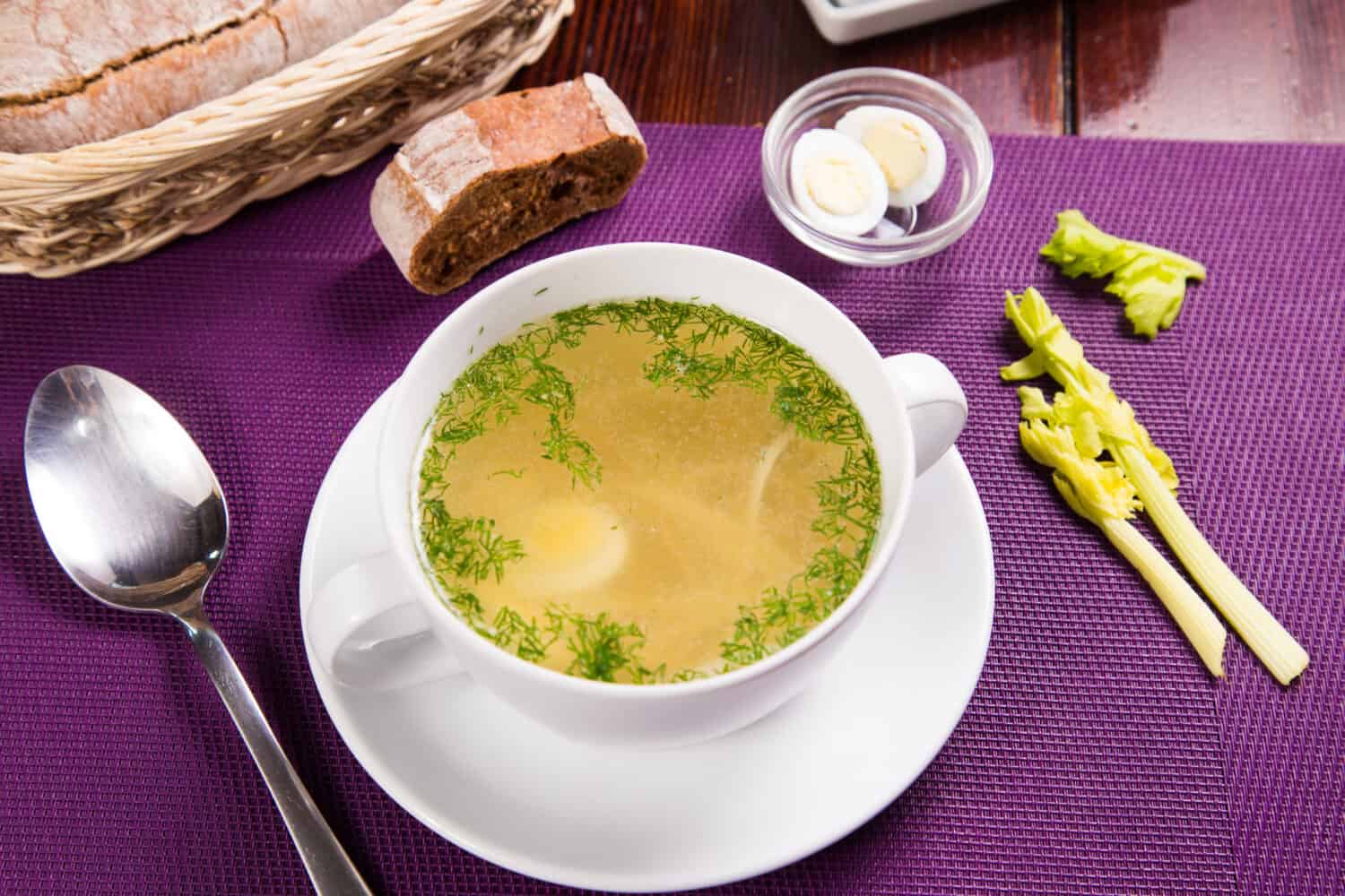 hot fresh soup with eggs and dill in white dish