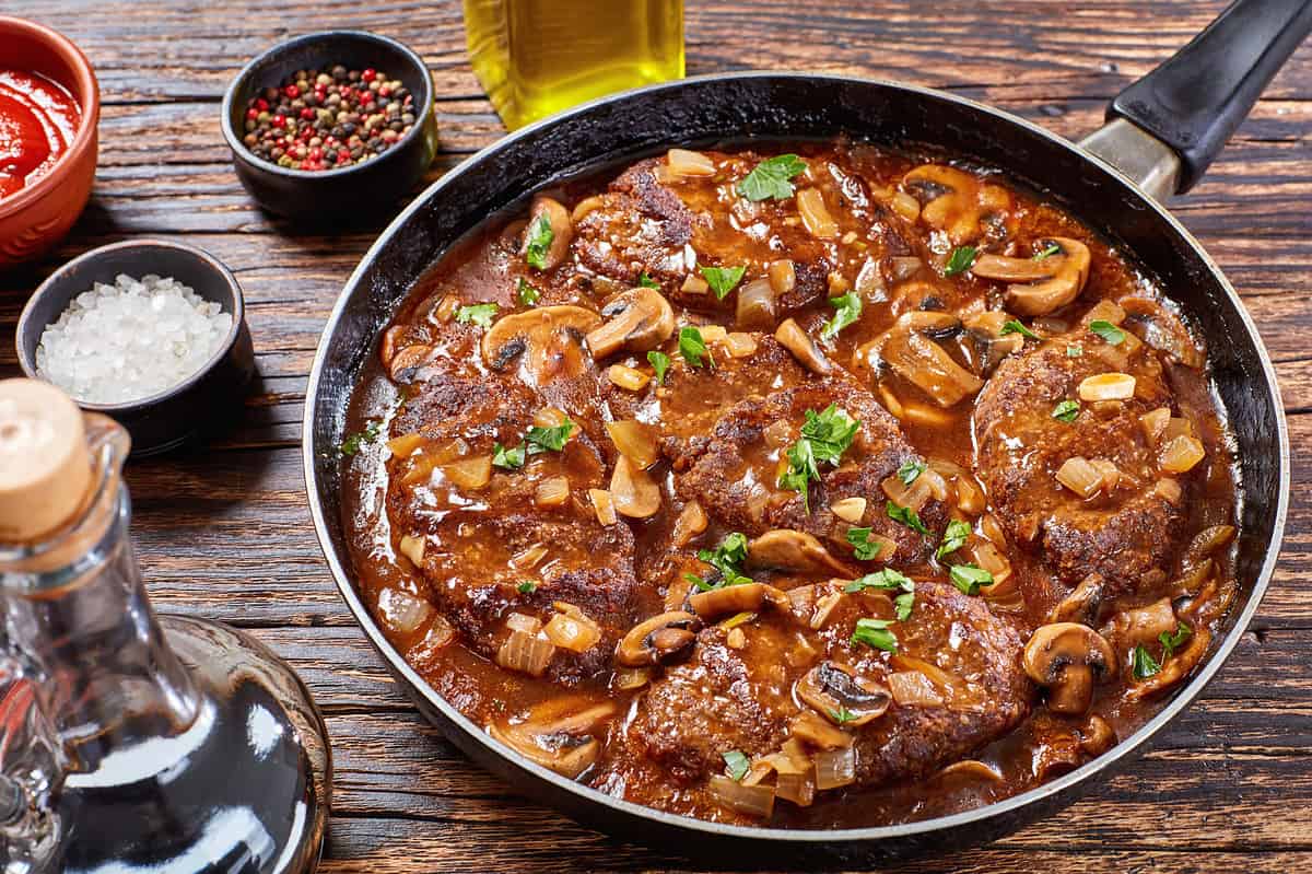 Salisbury steak cooking on a stove top pan